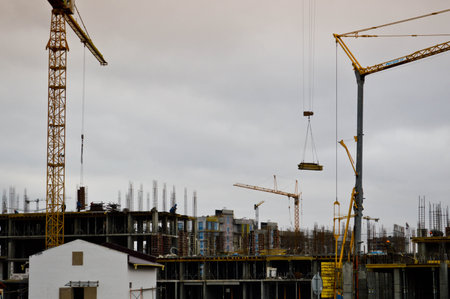 Working male builders are working on the roof of a large monolithic frame house, building, and new...