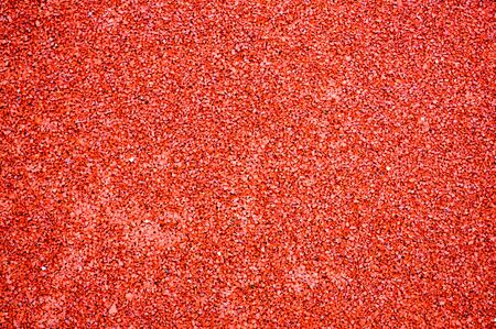 Red bright soft rubber flooring safe for sports and workout or on the playground from the many small round pebbles pressed. Background, texture.の写真素材