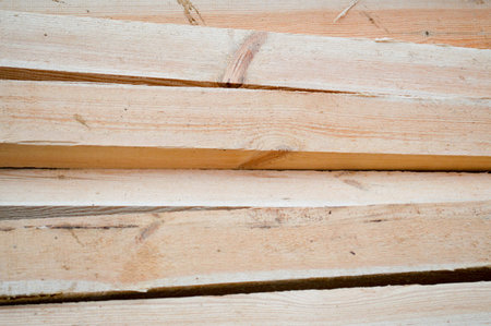 Lots of long wooden natural planed boards and sticks at a sawmill. The background. Texture. Concept:...