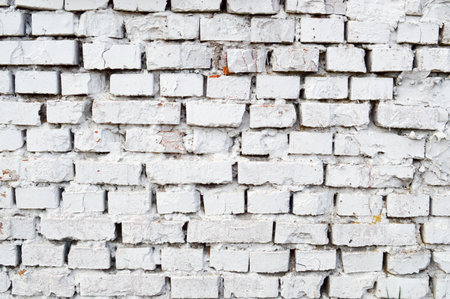 Beautiful white painted brick wall shabby old with cracks in the loft style with seams. Texture,...