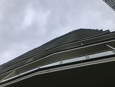 house of an unusual shape in white in the city center. view from below. unusual ledges where...