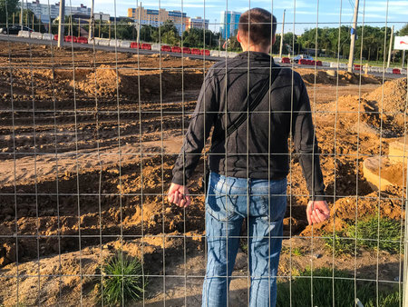 a young strong guy stands behind a metal fence and holds his fingers to it. protest mood. rally. the...