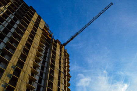 construction of a new multi-storey building. tall orange crane builds floors. carrying heavy and...