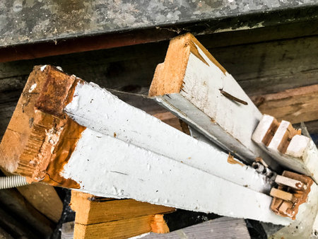 boards painted white are stacked vertically. thin bars are in a bucket. nails stick out in the...