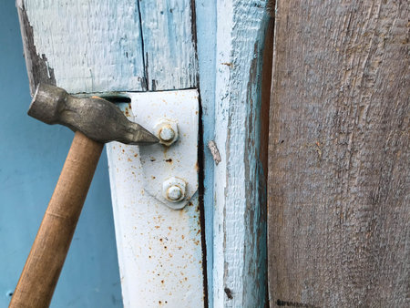 hammer on a wooden handle with a metal end. hammer nails into a metal surface. metal sheet is...