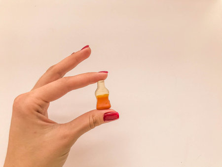 marmalade candies. a girl with a red manicure holds sweets in the shape of a bottle with lemonade....