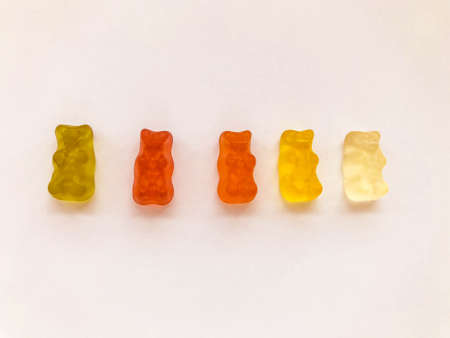 gummy bears of bright, different colors on a pink matte background. delicious mouth-watering candies of an unusual shape. high-calorie, cute dessert.の写真素材