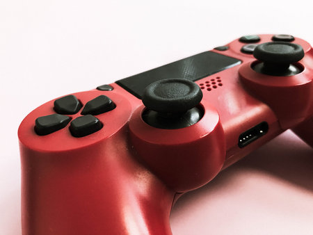Beautiful red digital modern new game joystick for computer video games gamepad on a pink...