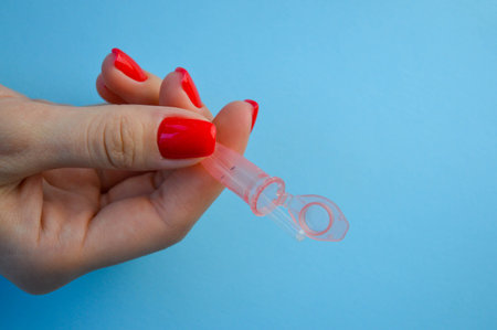 Test tube with blood sample to COVID-19 in fingers of doctor or scientist. Arm of medic with protective gloves testing blood samples on lab. Concept of health and safety life from pandemic.の写真素材