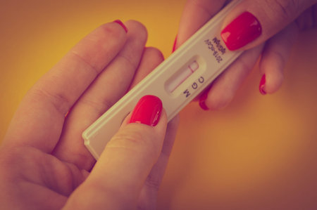 test for on an orange background. medical analysis. a girl with a bright red manicure holds an...