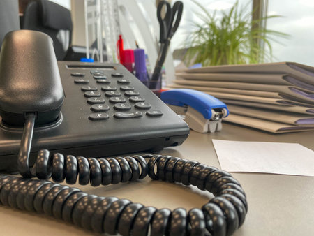 Gray and black business wired phone with receiver, dial and large display in the business office...