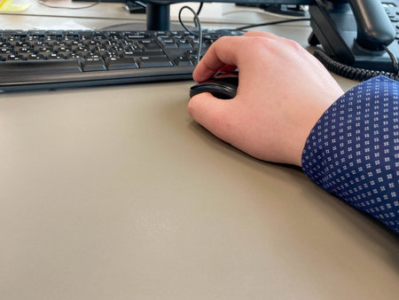 Male hand on a black computer mouse on the table in a modern business office.