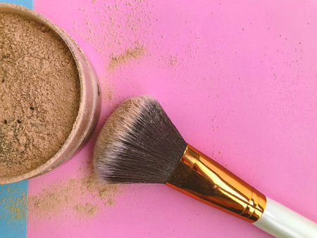 Makeup brush and powder in a brown jar. Powder for girls with dark skin. Powder for contouring on a...