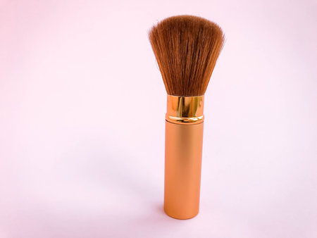 Make up brushes with powder splashes isolated on pink background.
