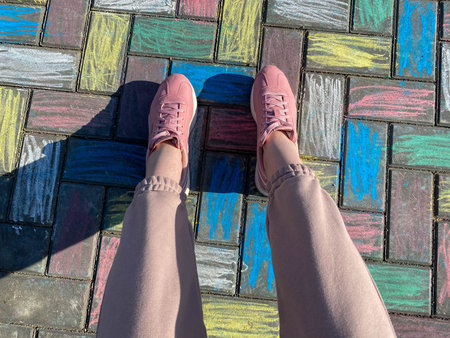 Beautiful female legs in pink sneakers and fashionable pants on a background of concrete paving...