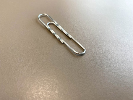 Shiny metal paper clips on a desktop with stationery in a business office. Close view.