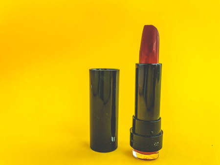 Beautiful fashionable beauty cosmetic glamorous red lipstick for applying makeup on the lips on a yellow gentle background.の写真素材