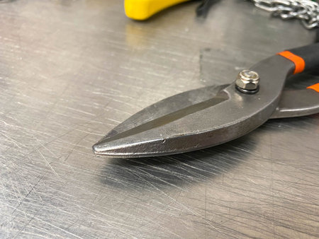 Large iron sharp metal scissors metal cutters lie on an iron table. Hand-held locksmith tools. The...