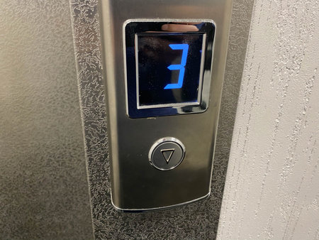 Metallic shiny chrome plated modern elevator call button with floor designation display in modern...