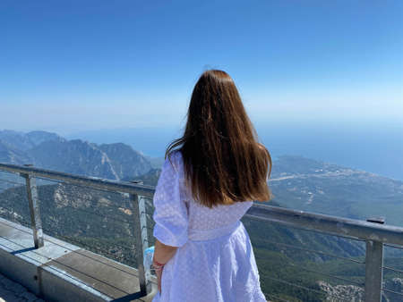 Back view of a traveling woman looking at an amazing view with cliffs and a tropical beach. Pointing to the mountain. The concept.の写真素材