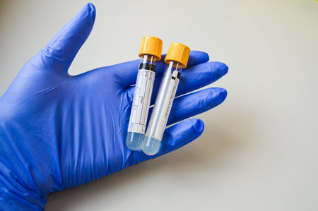 Hand in glove holding test tube on blurred background.の写真素材