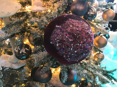 Close up of stylish Christmas tree toys and garland lights on branches.