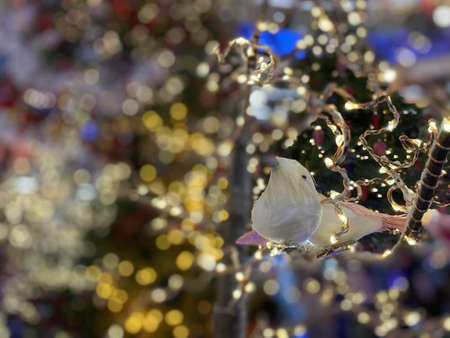 Christmas tree with Christmas toys: small bird, cones, balls, colored lights. Concept: New Year, greeting card, celebration. Soft focus. Festive bokeh.の写真素材
