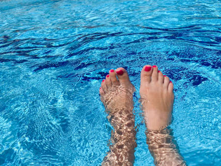 Bare woman feet on wooden deck by the swimming pool.の写真素材