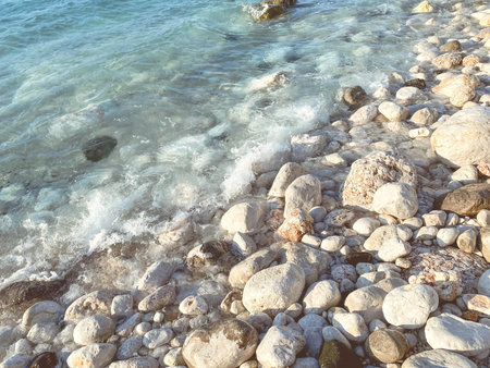sea coast. stones in the water. small and large stones lie among the water on the coast. a white sea...