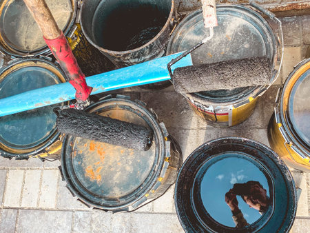 construction site. there are paint cans on the ground. on them lies a wali in black paint. preparation of materials for application on walls, decorative plaster.の写真素材