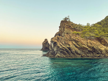 green mountains with plants above in the sea. a rock in the water, a tiny island for sailors. tourism resort. travel in hot countries.の写真素材