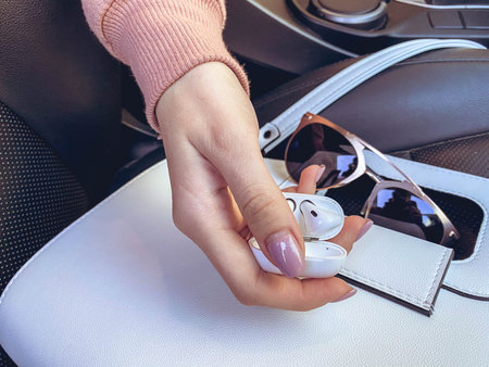 a girl with a pink manicure holds headphones without wires in her hands. flatley. bag and glasses...