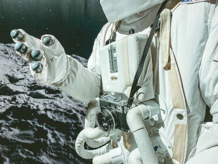 white suit with spacesuit astronaut in space. He has a camera hanging around his neck. on the suit of a tube to ensure the astronaut's breathing.の写真素材