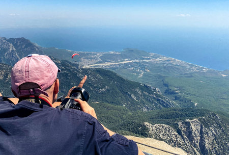 tourists on the observation deck. a man in a white cap photographs a bird's eye view. in his hand he has a big black camera with a lens.の写真素材