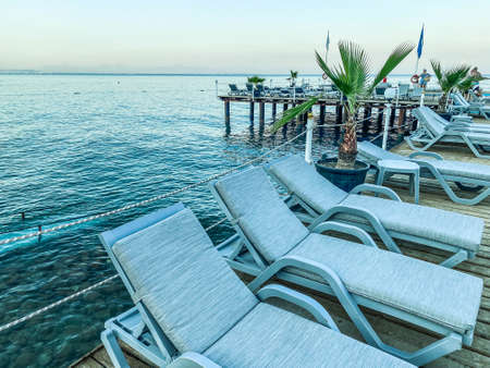 hot, tropical country with sea and mountains. pontoon made of wood for diving into the water with sunbeds made of white fabric. tall palm trees grow nearby.の写真素材