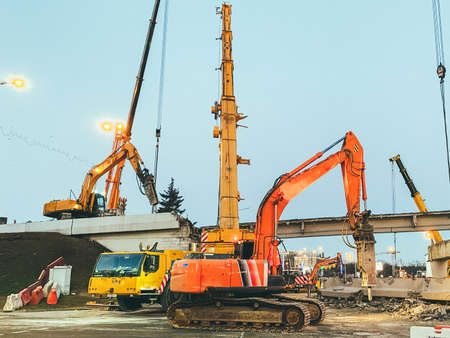 construction of a broken bridge on a busy road. the chipper makes a hole in the asphalt to replace it. repair of the bridge behind the barrier for the passage of people.の写真素材