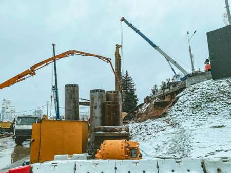 long, black, narrow pipes for laying plumbing communications. metal pipes are covered with a layer of snow. sewer disposal. renovation work in a residential area.の写真素材