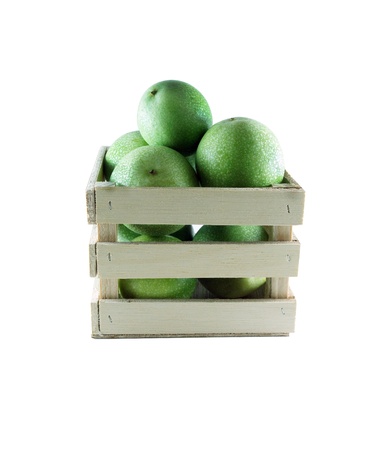 Green pomegranates in a wood box on white background.の写真素材