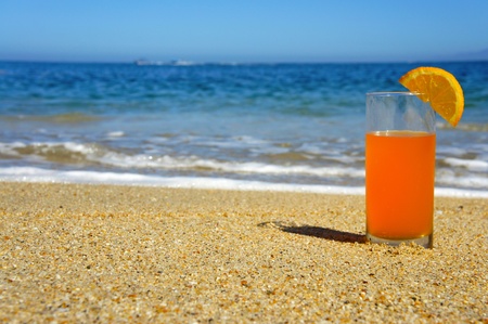 A glass of Orange Juice standing in the sand の写真素材