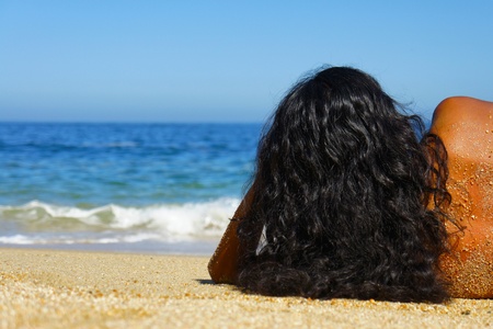 Young woman laying on beach sun tanning の写真素材