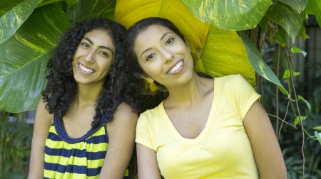 2 Girl friends smiling and leaning against a tree.の写真素材