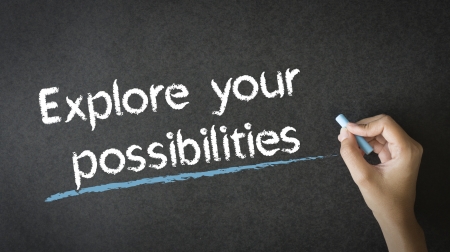 A person writing Explore Your Possibilities with chalk on a blackboardの写真素材