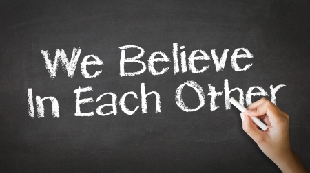 A person drawing and pointing at a We believe in Each Other Chalk Illustrationの写真素材