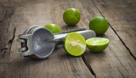 Old hand juicer with limes on wooden backgroundの写真素材