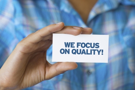 A person holding a white card with the words We focus on qualityの写真素材