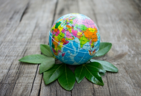 A globe standing of a pile of leaves on wood background. の写真素材