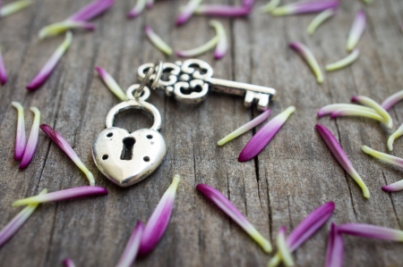 Key with heart shaped lock charm on wooden background.の写真素材