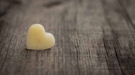 A beige heart out of wax on wooden backgroundの写真素材