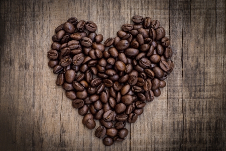 A heart shaped out of coffee beans on wood backgroundの写真素材