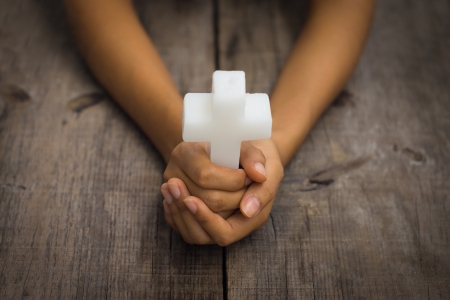 A person holding a white Religious Cross on white backgroundの写真素材